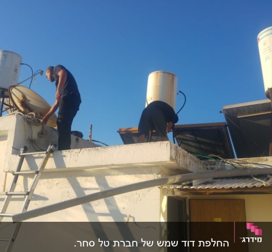 אנשים מתקנים דוד שמש על גג עם קולטים